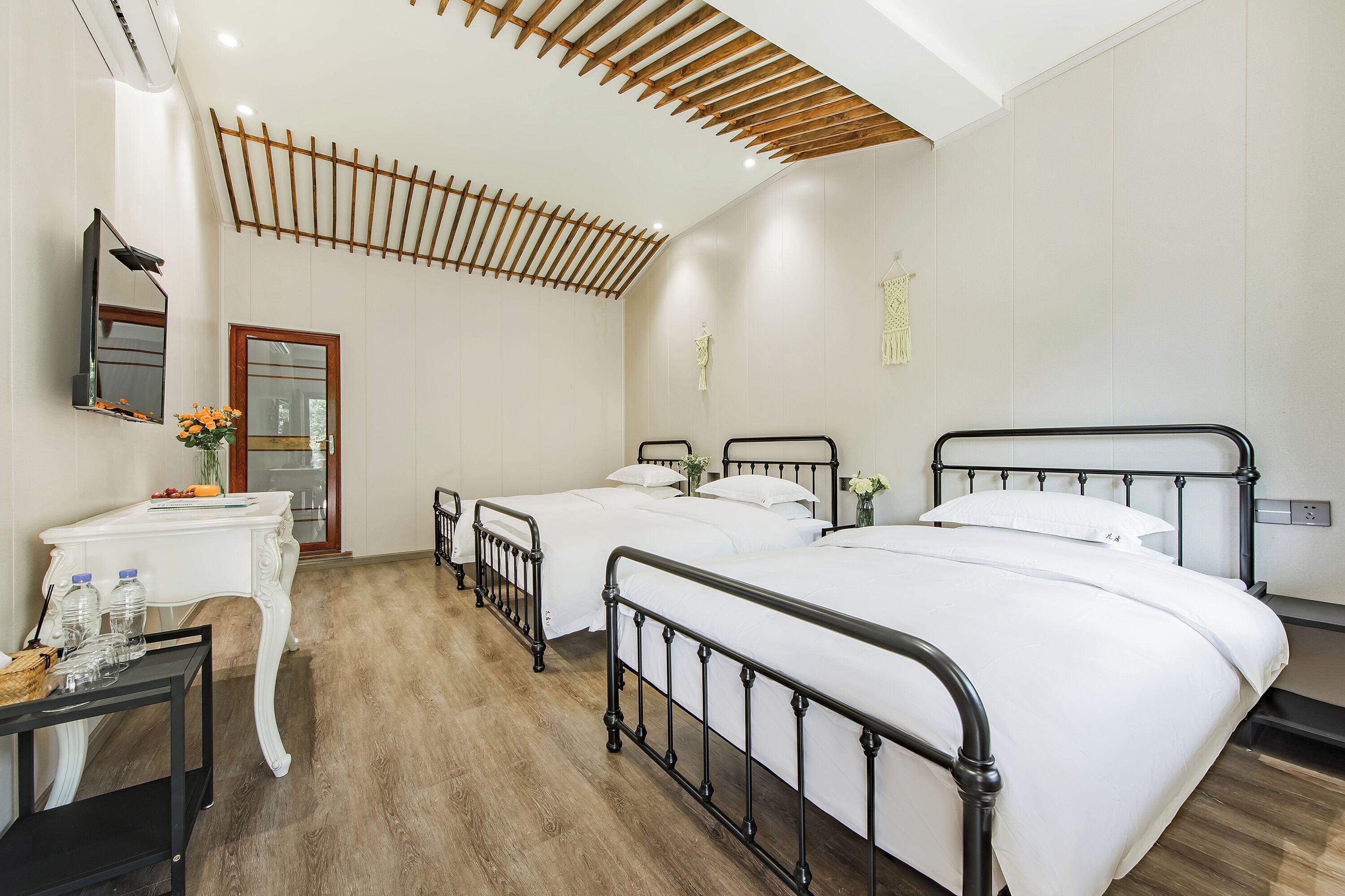Una habitación de hotel con dos camas, un escritorio con espejo y techo de madera.