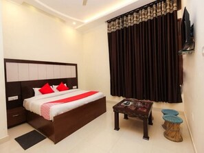 A modern hotel room with a large bed, a small table, and a TV. - Hotel Ambika & Restaurant By GRB (Palampur)
