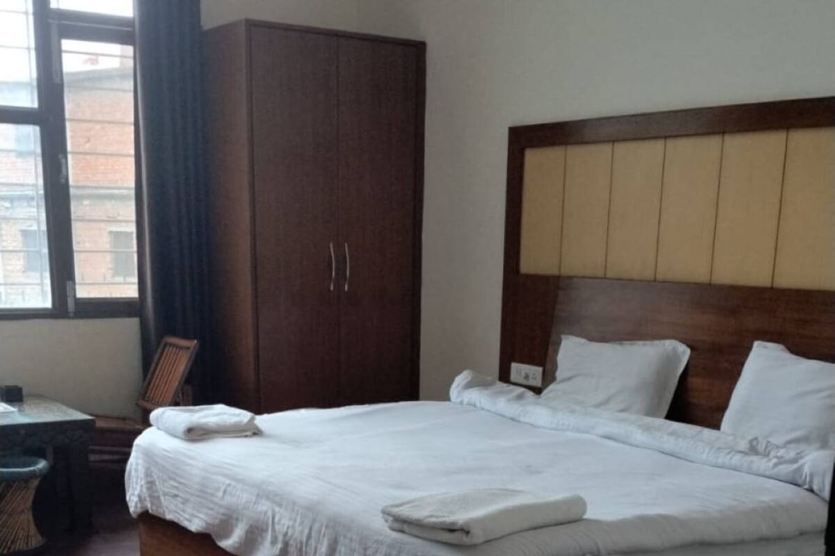 Un lit bien fait, avec du linge de lit blanc, une tête de lit en bois et une grande armoire.
