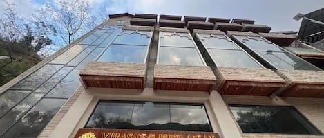 Ein Hotel mit modernem Design, das große Glasfenster und ein auffälliges Schild für "VIRASAT-E-BUSHAHAR A BOUTIQUE HOTEL" zeigt.