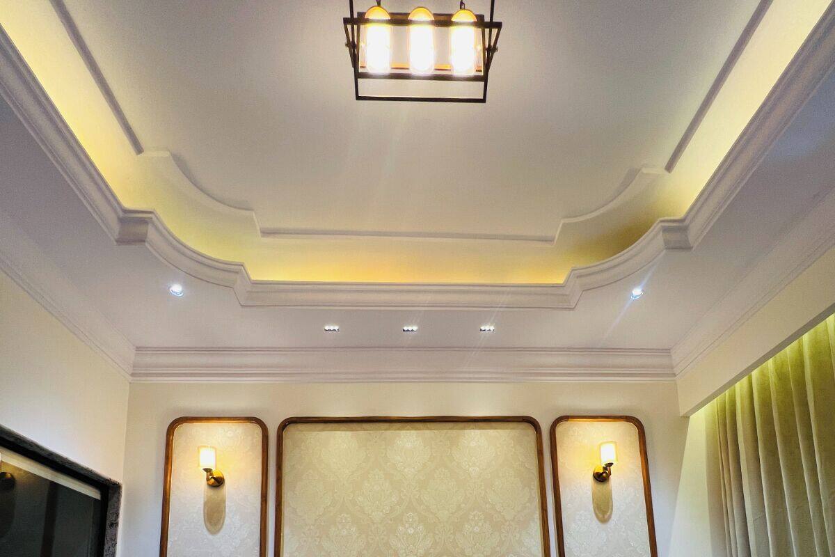 Une chambre d’hôtel avec un grand lit, deux tables de chevet, une lampe fixée au mur et une fenêtre avec des rideaux.