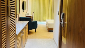 Ein modernes Hotelzimmer mit einem Holzschrank, einem Bett, einem Schreibtisch und einem Stuhl.