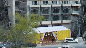 Ein mehrstöckiges Gebäude mit einem Uhrturm, Balkonen und einem überdachten Eingang.