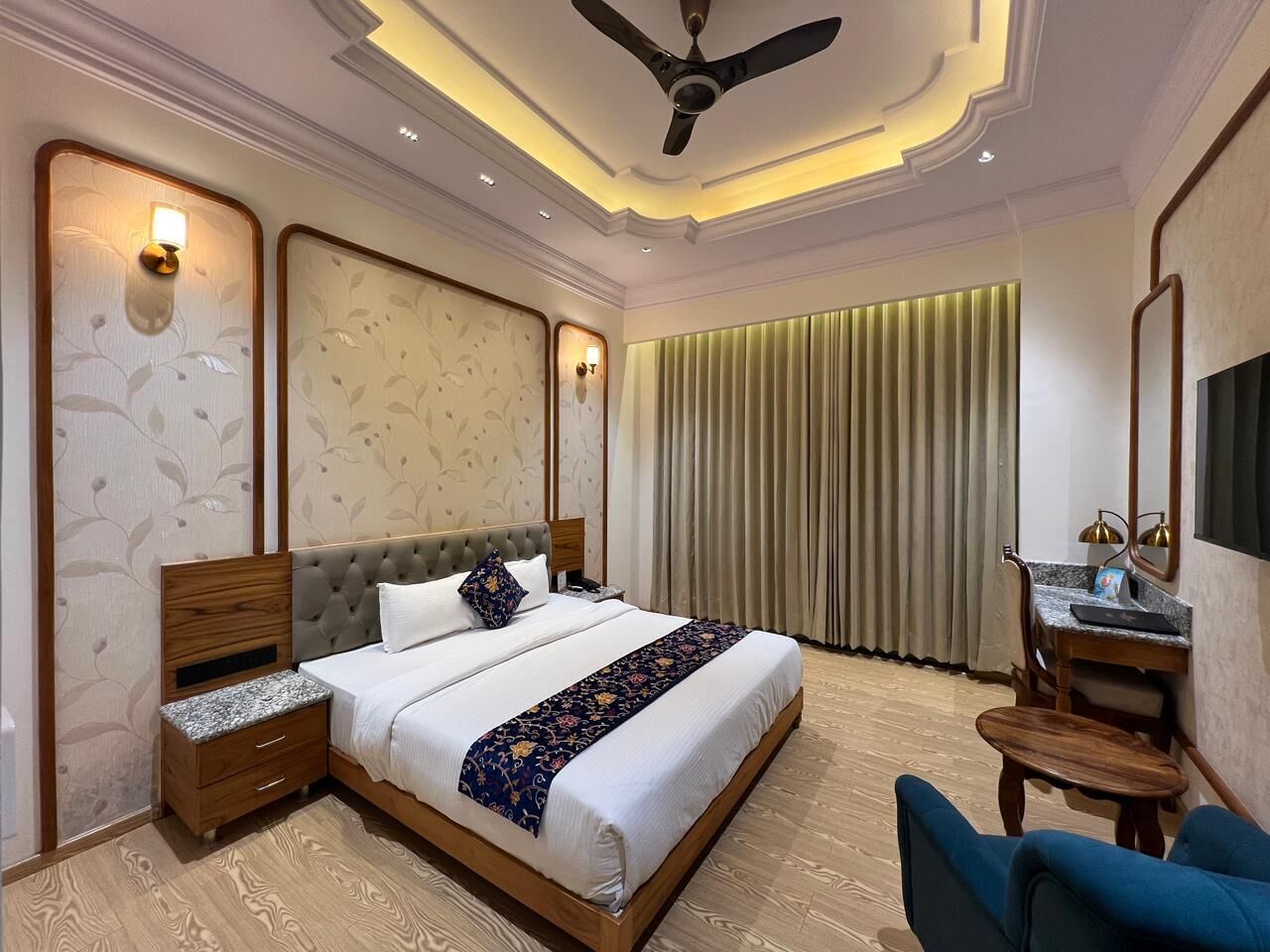 A modern hotel room with a large bed, a desk, and a chair.