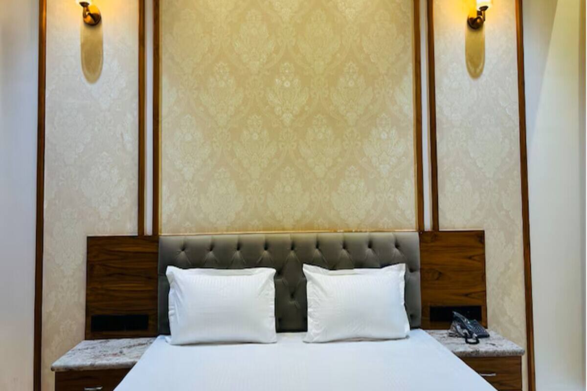 Un lit avec une tête de lit capitonnée, deux tables de chevet et des appliques murales.