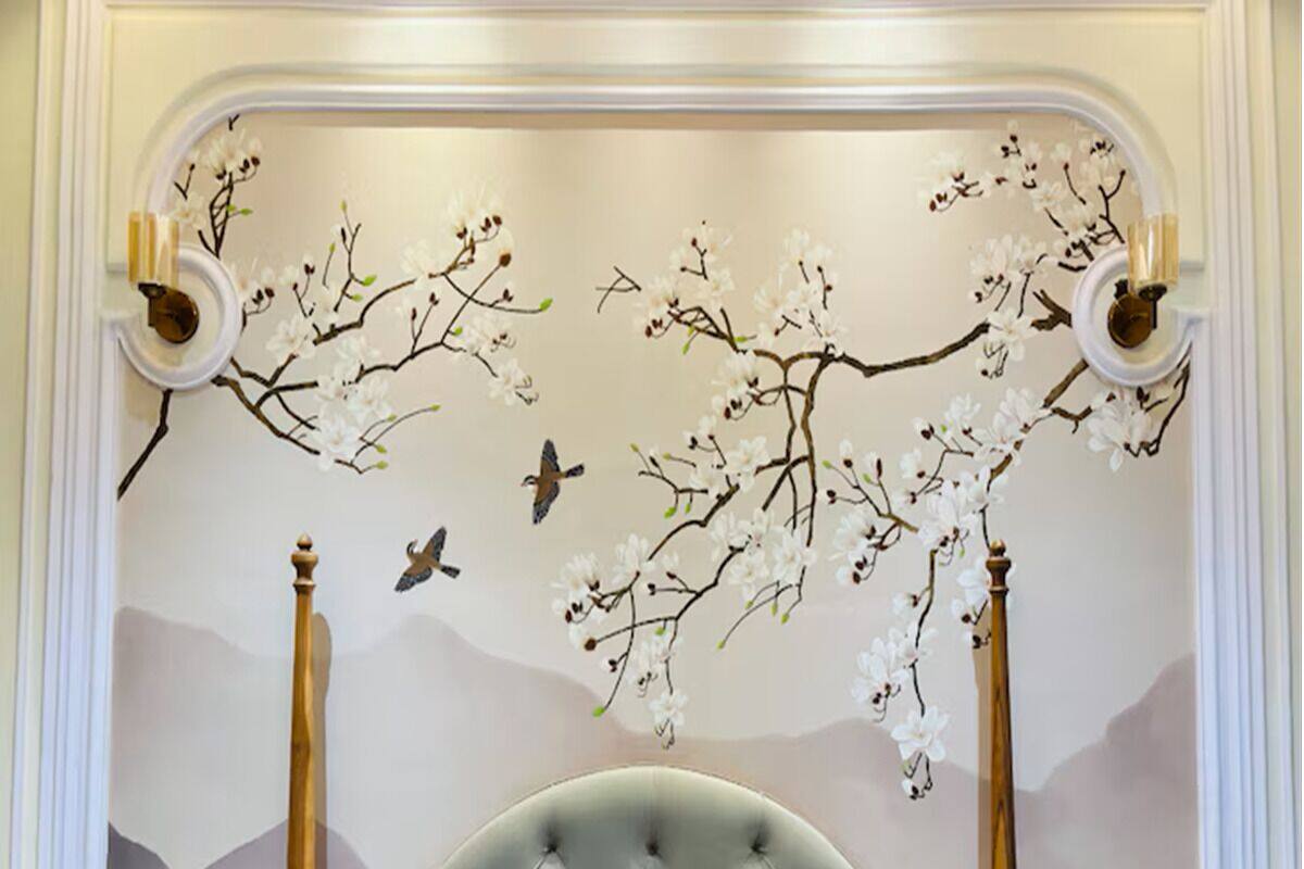 Une chambre dotée d’une tête de lit capitonnée, d’une fresque représentant des fleurs de cerisier et des oiseaux, et de deux appliques murales.
