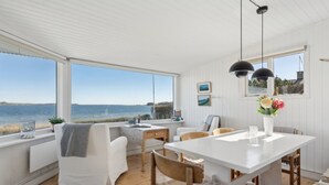 Un espacio habitable amplio y luminoso con vistas al mar, una mesa de comedor y una zona de estar acogedora.