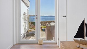 Una habitación con puerta corrediza de vidrio que da a un balcón con vista al mar.
