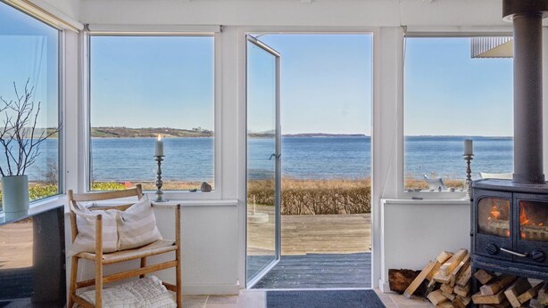 Una habitación acogedora con un ventanal grande que da a una masa de agua, una chimenea y un espacio de estar confortable.