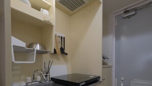 A compact kitchen with a sink, shelves, and a microwave.