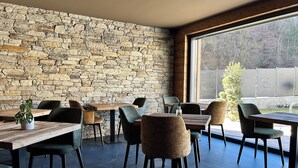 A restaurant with stone walls, wooden tables, and modern chairs. - Rustic and alpine-style apartments in Ledro Valley (Tiarno di Sotto)
