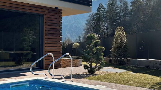 A modern house with a swimming pool, wooden deck, and a view of mountains. - Rustic and alpine-style apartments in Ledro Valley (Tiarno di Sotto)