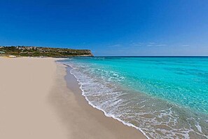Une plage à l’eau turquoise et limpide, bordée d’un rivage sablonneux.