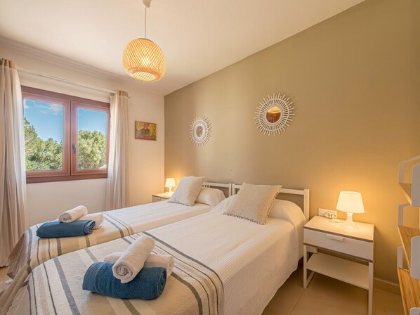 A double room with two beds, a window with curtains, a hanging light fixture, and a bedside table with a lamp. - Alta Mar apartment Son Bou (San Jaime Mediterráneo)