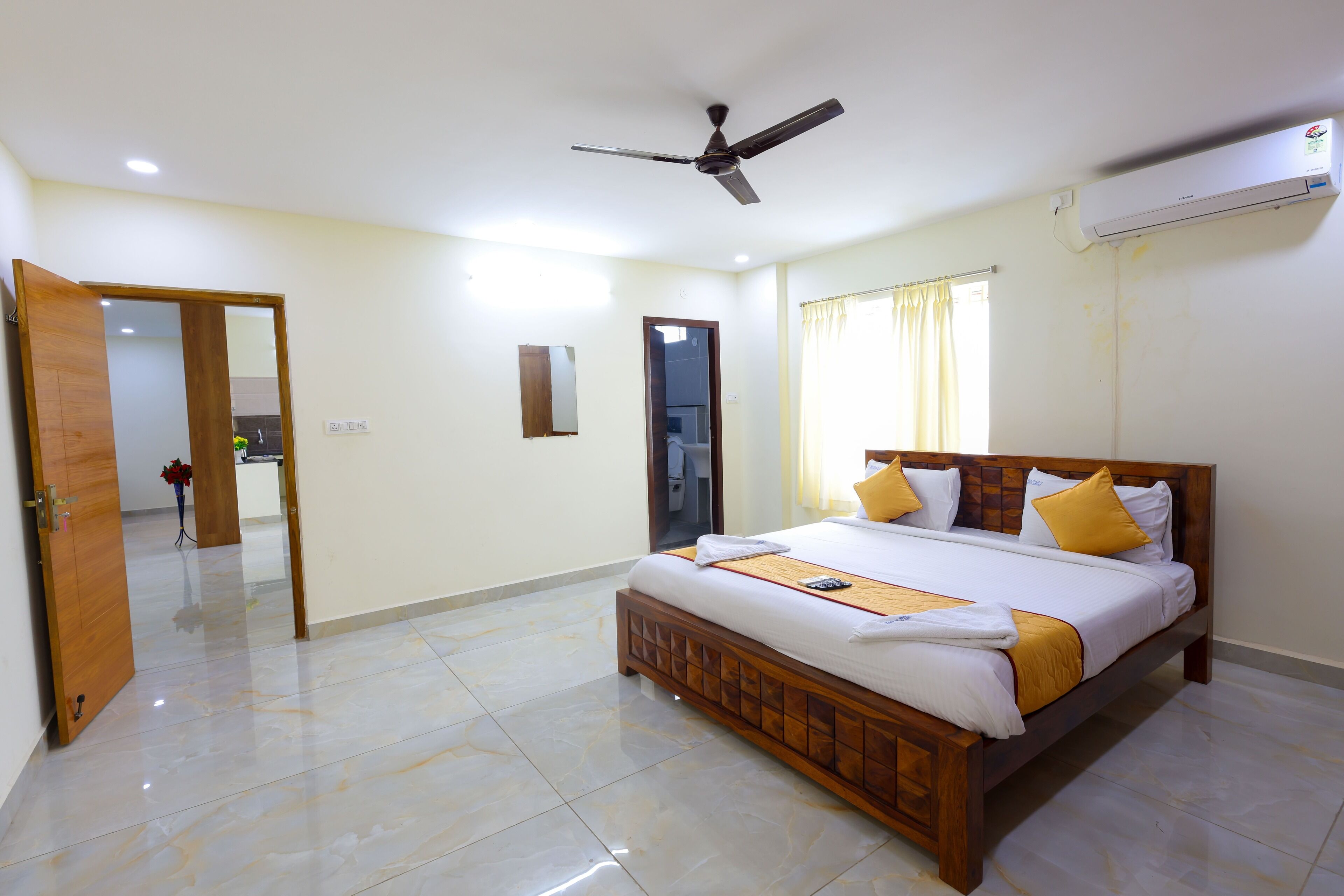 A spacious bedroom with a large bed, a ceiling fan, and an air conditioning unit.