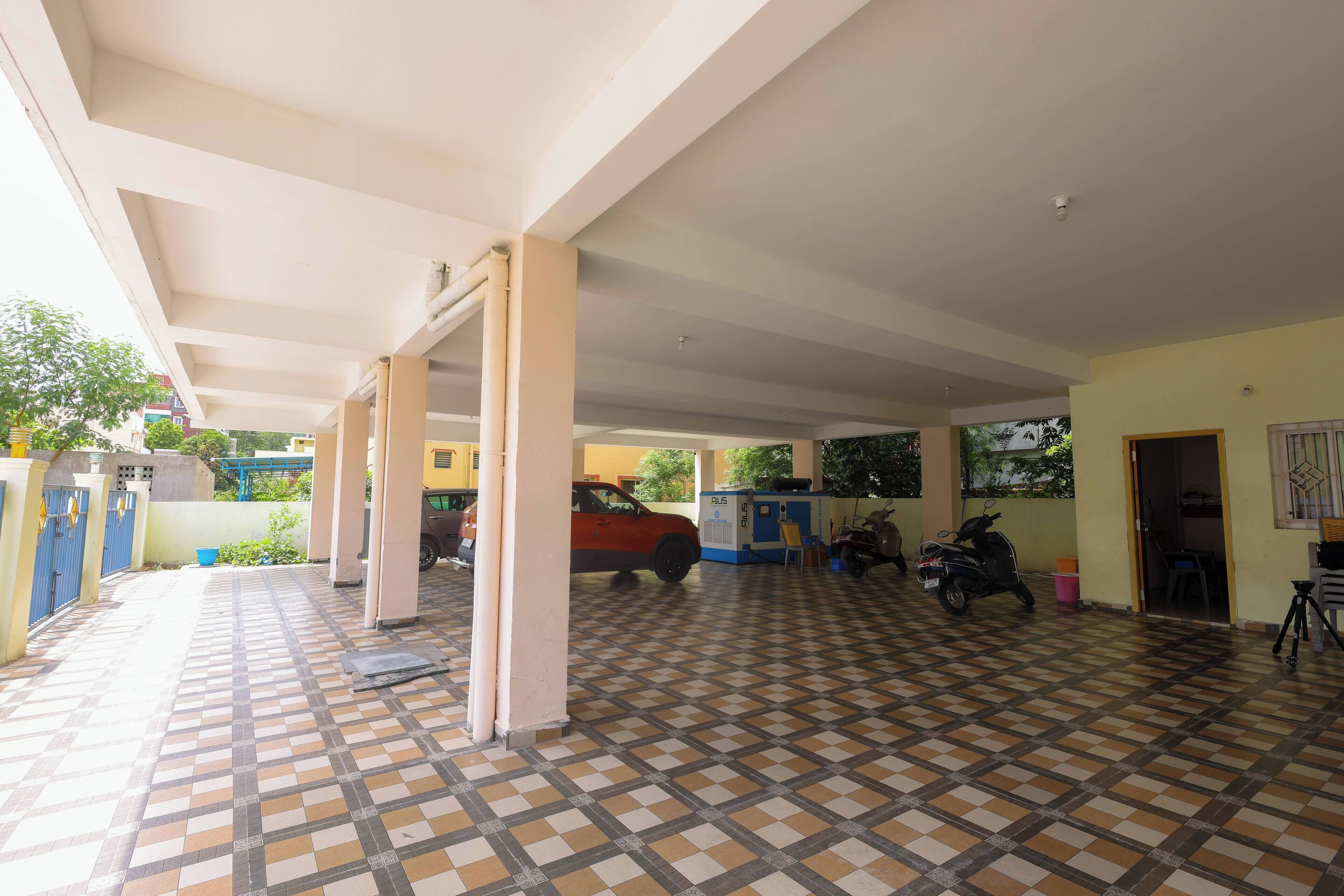 A covered parking area with a tiled floor, pillars, and a parked car.