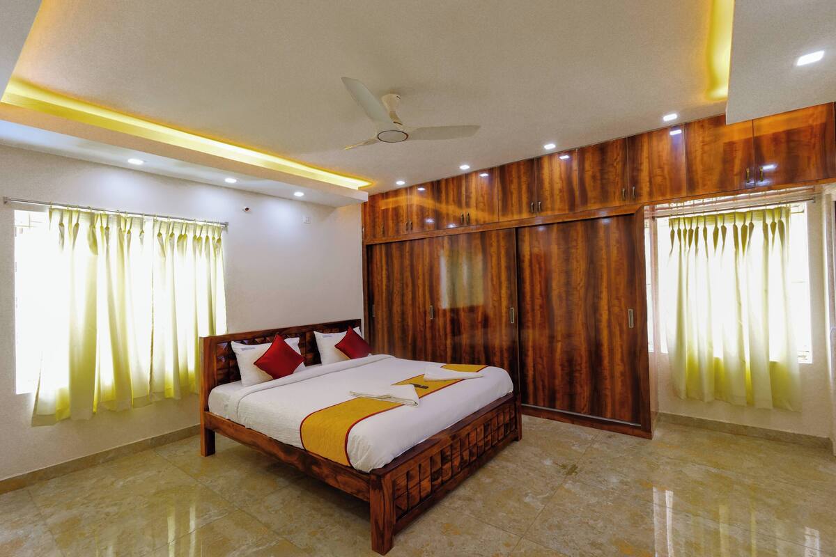 Quarto bem arrumado com cama, guarda-roupa de madeira e ventilador de teto.