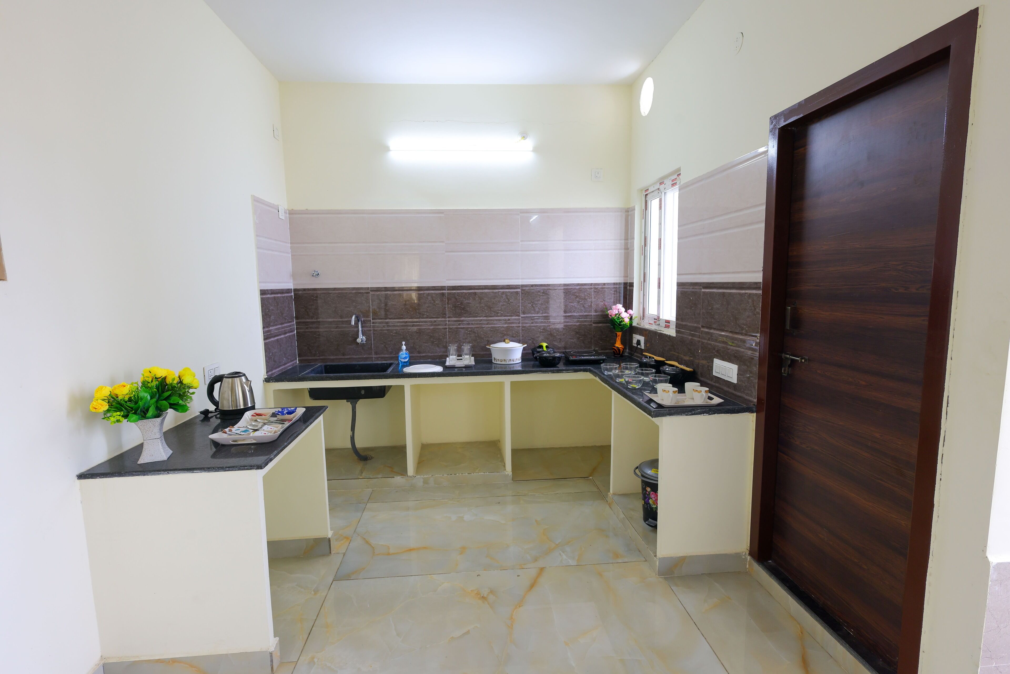 Una cocina compacta con una puerta de madera oscura, una pequeña encimera con un jarrón de flores y un salpicadero de azulejos.