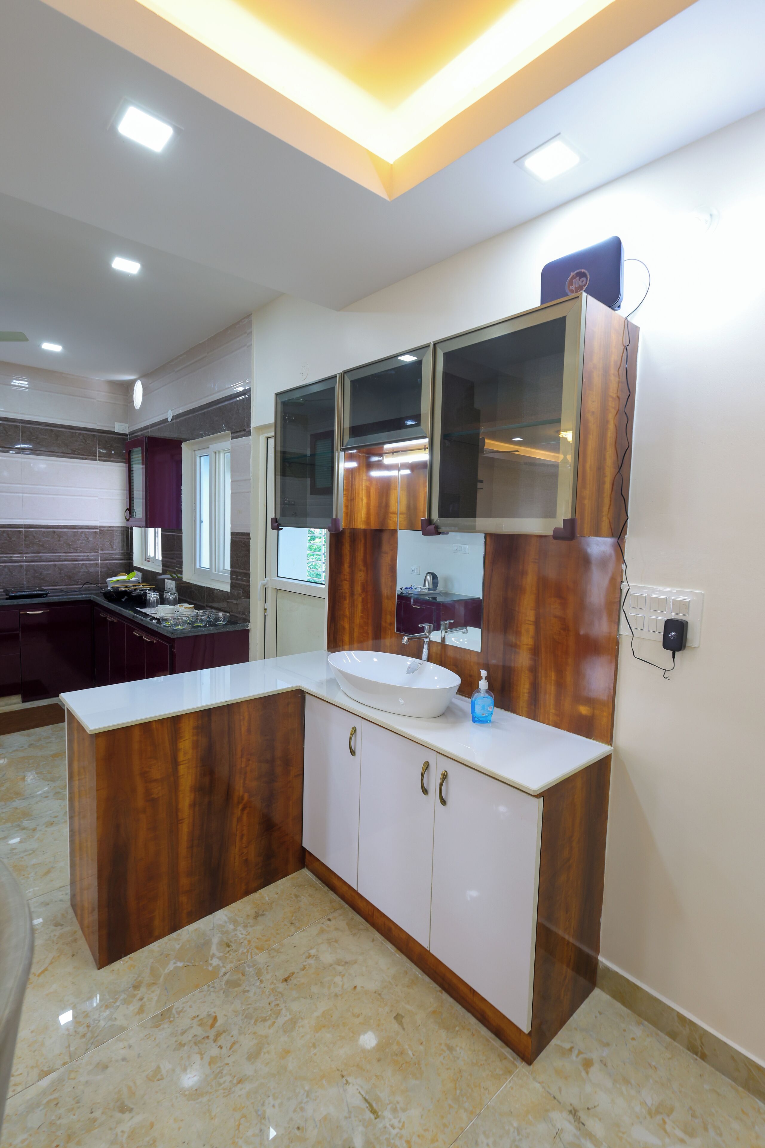 A modern kitchen with a marble countertop, wooden cabinets, and a built-in sink.