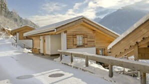 A row of wooden cabins with snow-covered roofs, set against a mountainous backdrop. - Quiet Alpine Cottage for 9 with Suana (Wald-Königsleiten)