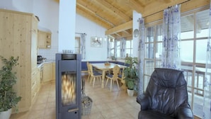 A spacious living area with a fireplace, wooden ceiling, and large windows.