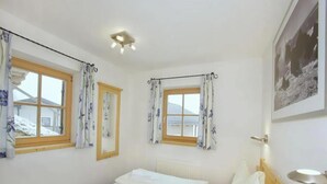 A room with two beds, a window, a mirror, a radiator, and a picture on the wall. - Quiet Alpine Cottage for 9 with Suana (Wald-Königsleiten)