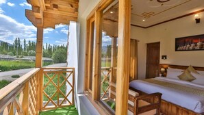 A bedroom with a large window, wooden balcony, and a bed with pillows. - Kangseng House (Leh)