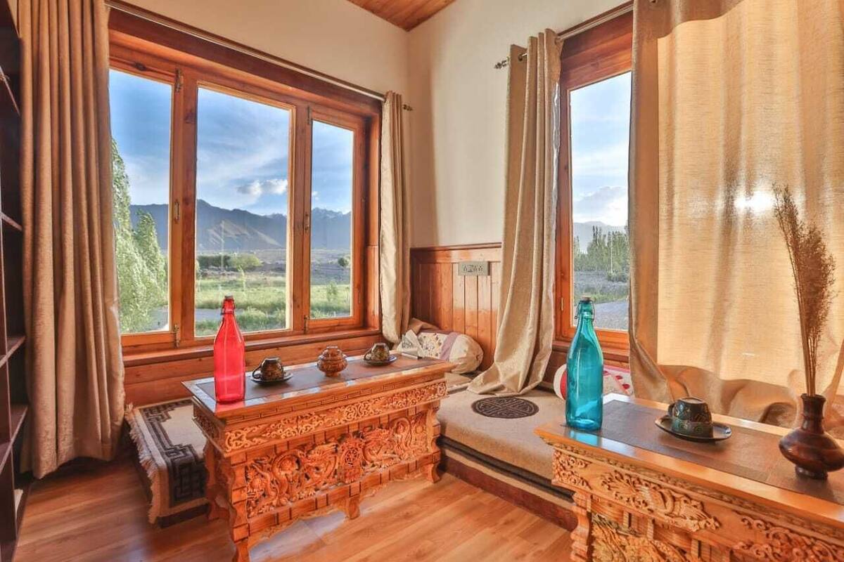 A cozy room with wooden furniture, large windows, and a view of mountains.