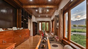 A long wooden hallway with a view of a mountainous landscape through large windows. - Kangseng House (Leh)