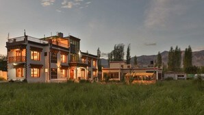 A multi-story house with a balcony, large windows, and a flat roof. - Kangseng House (Leh)