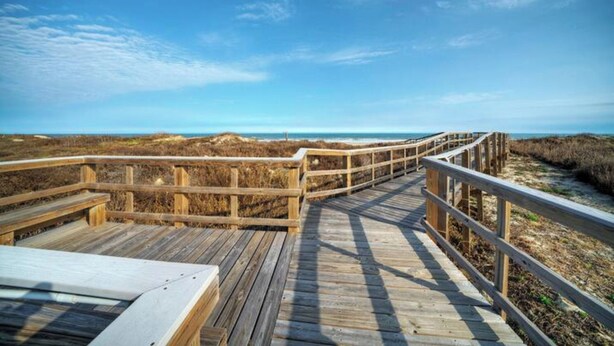 A wooden boardwalk leading to a beach with a clear sky. - Sleeps 20 | 3 Condos w/ Beach Access, Pool, Tennis Courts | Sea Sands Complex (Port Aransas)