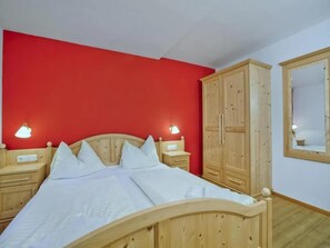 A bedroom with a wooden bed, two bedside tables, a wardrobe, and a mirror on the wall.