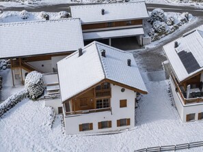 A snow-covered building with a sloped roof, wooden exterior, and multiple windows.