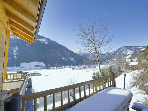 A wooden balcony with a view of a snow-covered landscape and mountains.