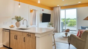 A modern kitchen with a central island, a dining area with a sofa, and a balcony with a view. - 2 Bedroom Suite w/ Balcony | 12South | New Hotel (Nashville)