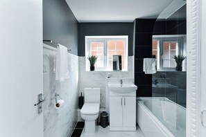 A modern bathroom with a toilet, sink, and bathtub. - 2-Bed in Quiet Area, Easy City & Transport Access (Nottingham)