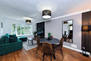 A modern living room with a sofa, dining table, chairs, and a large mirror. - 2-Bed in Quiet Area, Easy City & Transport Access (Nottingham)