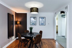 A dining area with a round table, four chairs, a pendant light, and framed artwork on the wall. - 2-Bed in Quiet Area, Easy City & Transport Access (Nottingham)