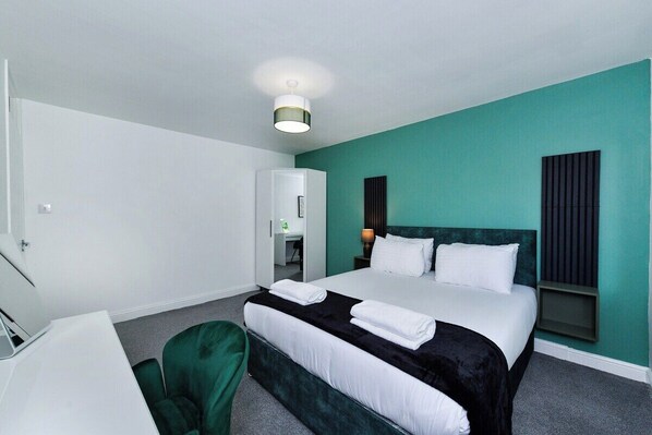 A hotel room with a bed, a desk, a chair, and a wardrobe.