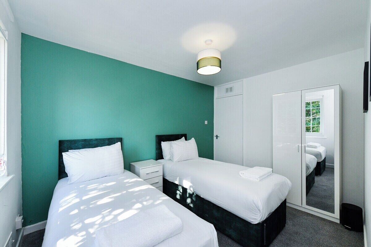 Ein Zimmer mit zwei Betten, einem Kleiderschrank und einem Spiegel.