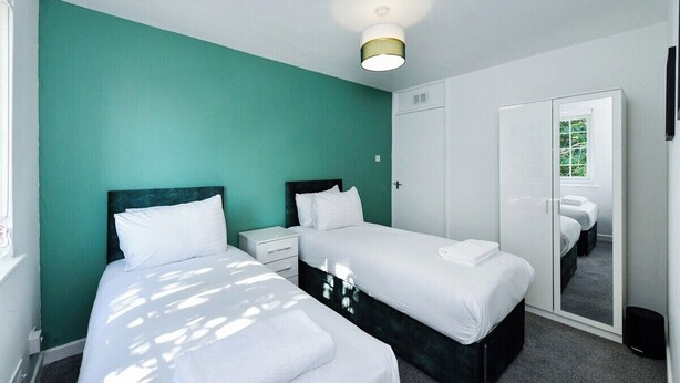 Quarto com duas camas, um guarda-roupa e um espelho.