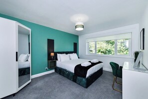 A modern bedroom with a bed, bedside table, lamp, and a window with a view of greenery. - 2-Bed in Quiet Area, Easy City & Transport Access (Nottingham)