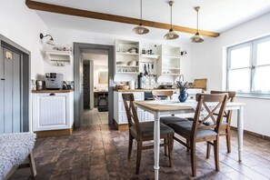 A kitchen with wooden chairs, a dining table, and built-in shelves with dishes and kitchenware. - Wonderful natural landscape for riding and hiking excursions (Komló)