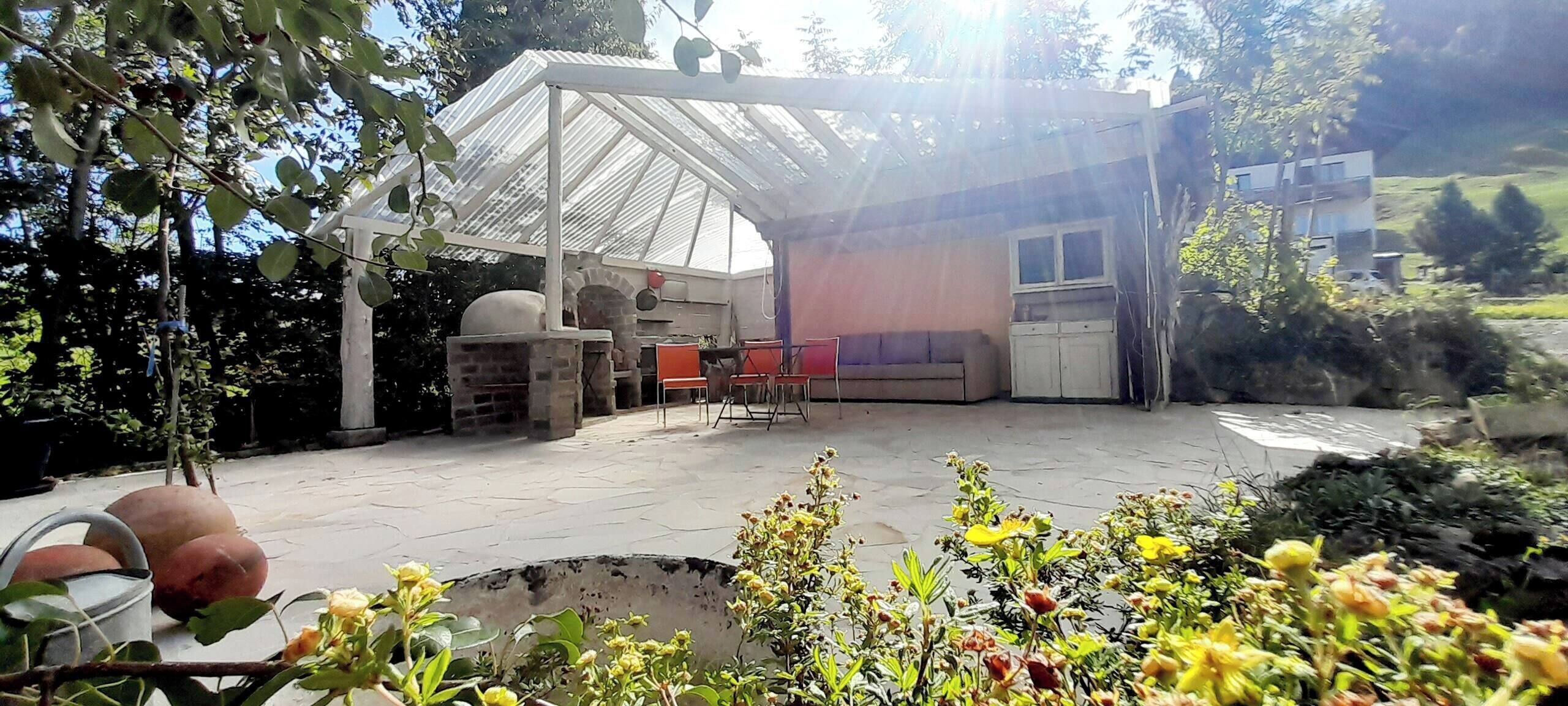 A covered patio area with a seating arrangement, a brick oven, and a water feature.