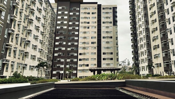 A modern high-rise residential building with multiple balconies and air conditioning units.