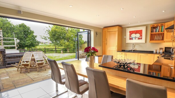 A modern kitchen with a dining area, large windows, and a view of the outdoors. - Witham View (Lincoln)