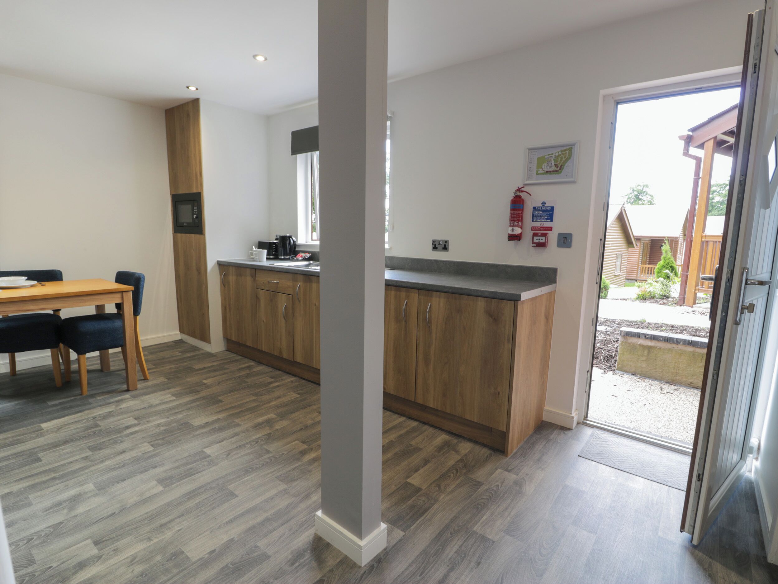 A modern kitchen with wooden cabinets, a dining table with chairs, and a view of the outside.