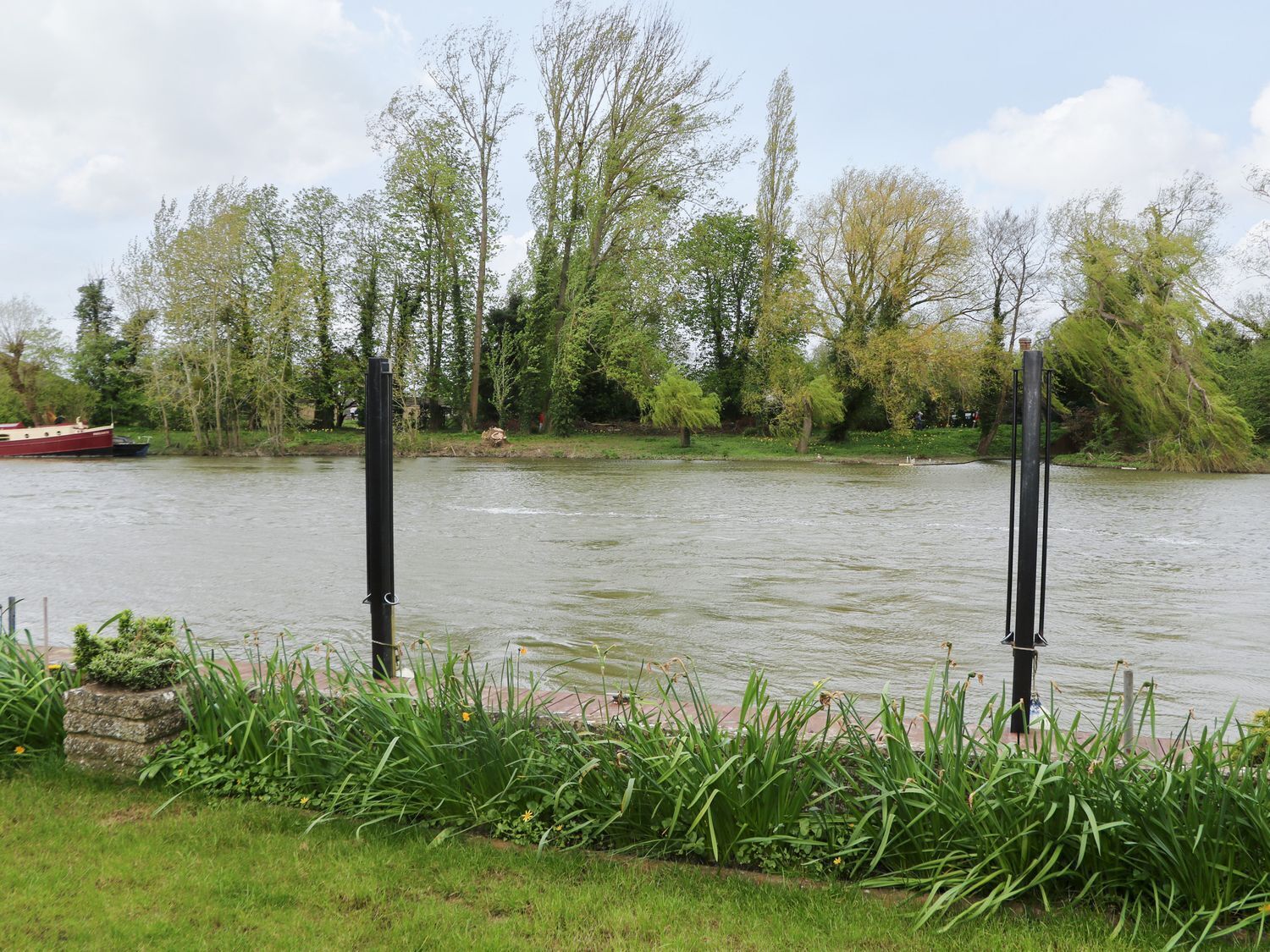 Un río con un bote amarrado a la izquierda, rodeado de follaje y árboles.
