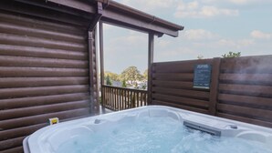 A hot tub with a wooden deck and a safety sign. - Luxury Lodge 53 (Rhyl)