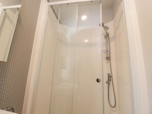 A glass-enclosed shower stall with a handheld showerhead and a wall-mounted faucet. - Giorgio (Preston)
